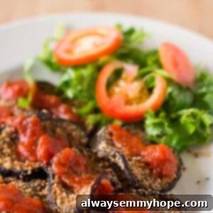 Baked eggplant on a white plate with salad.