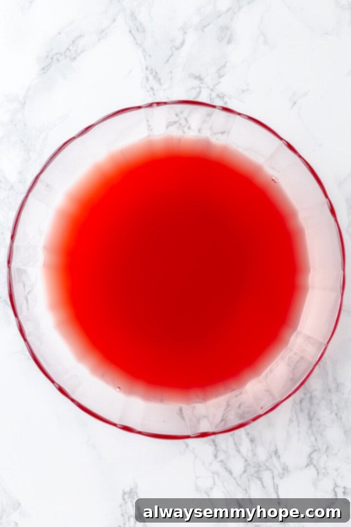 Overhead view of cranberry, apple, and orange juices being mixed in a large punch bowl.