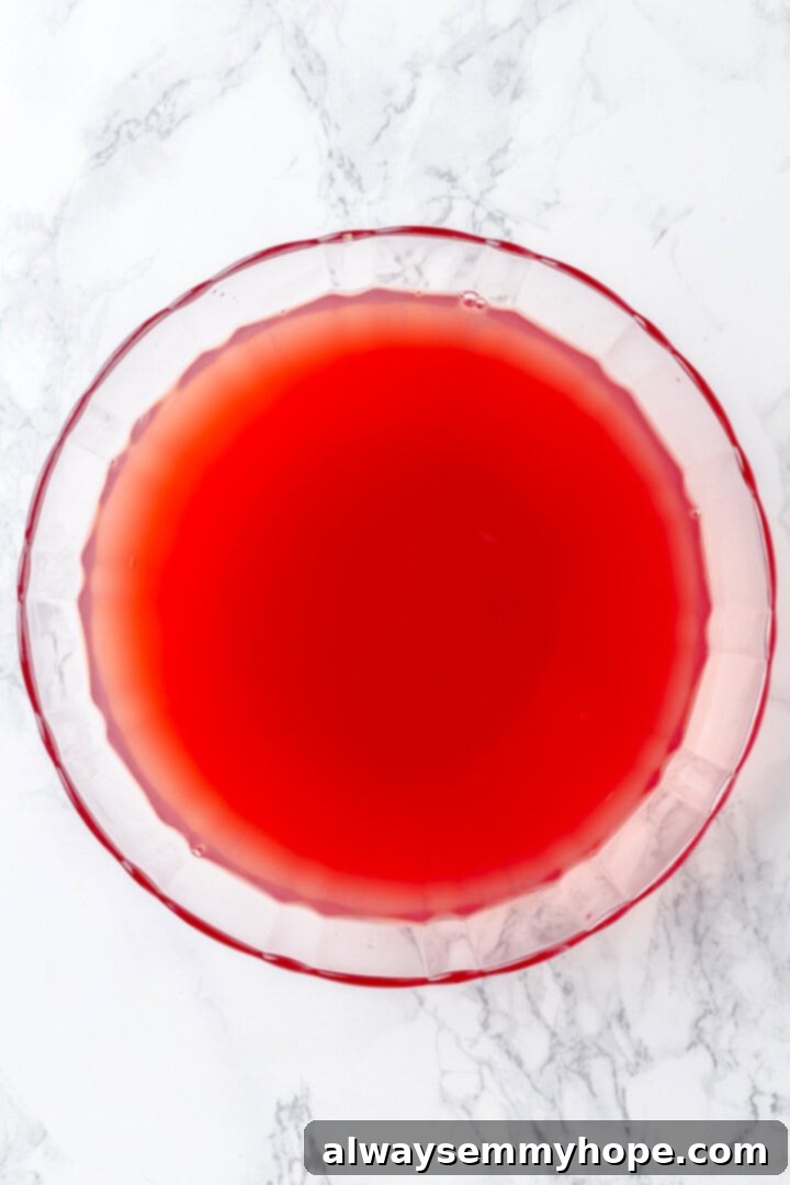 Overhead view of a punch bowl with mixed juices, as ginger ale or Prosecco is being poured in to add fizz.