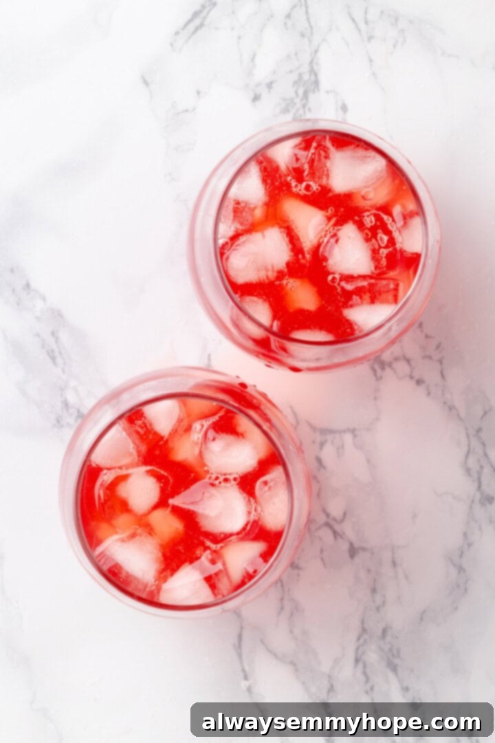 Overhead view of two glasses filled with ice and Christmas punch, beautifully garnished with orange slices and cranberries.
