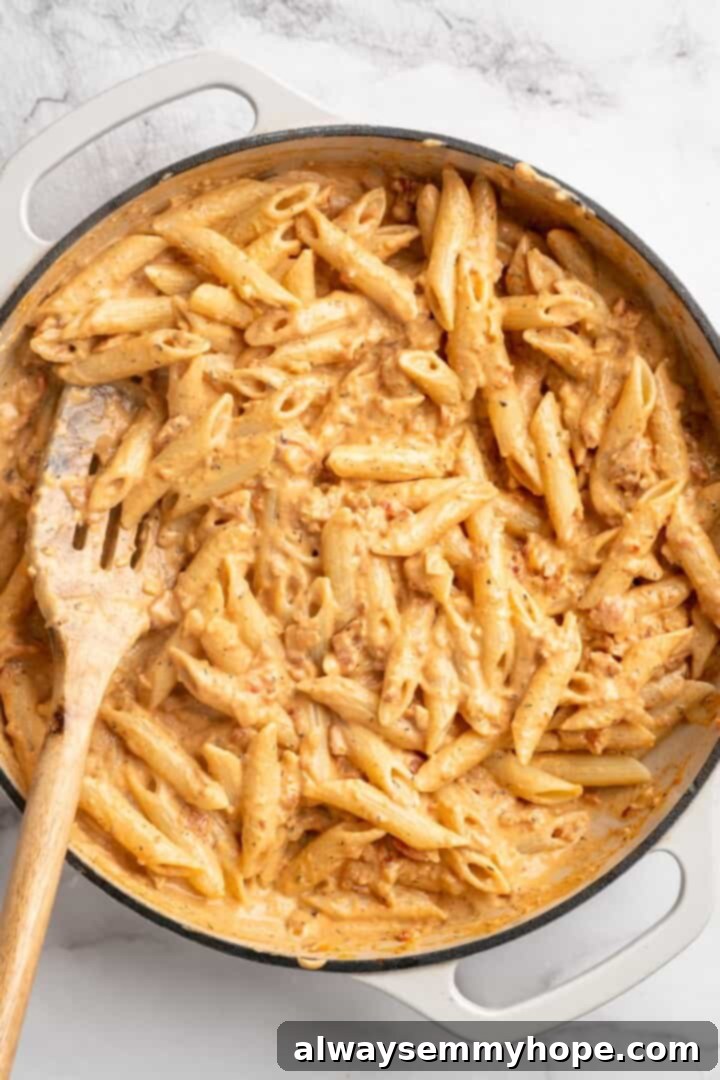 Stirring marry me pasta in skillet with slotted spoon