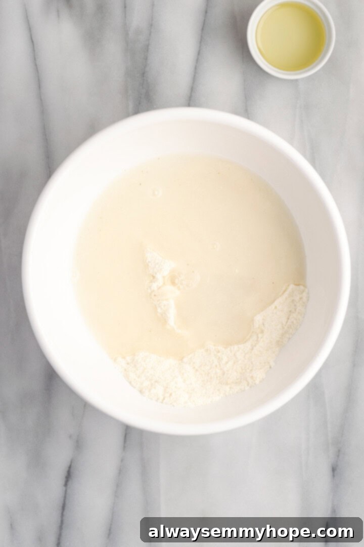 Overhead shot of masa harina, salt, baking powder, olive oil, and warm water being whisked together in a bowl to form the gordita dough.