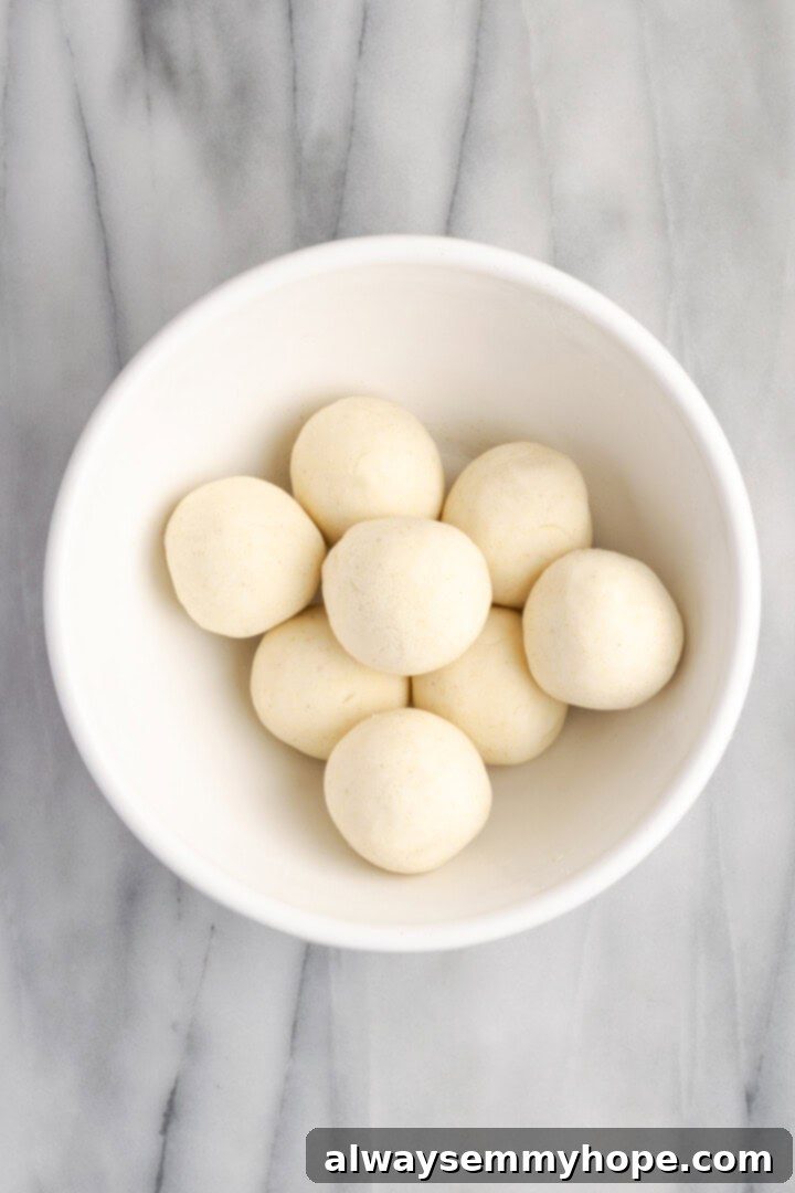 Overhead view of freshly kneaded gordita dough, divided into smooth, uniform balls, resting on a clean surface.