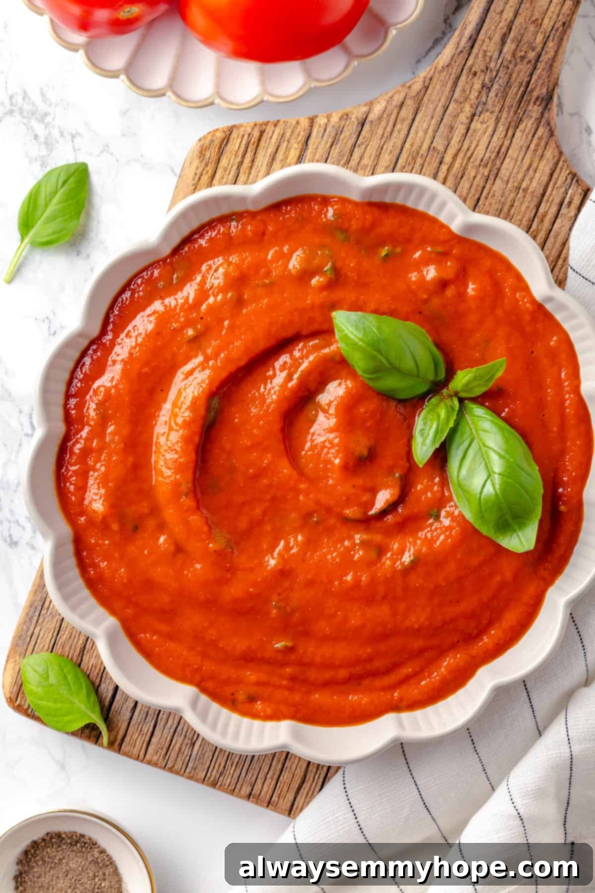 This homemade pomodoro sauce recipe takes a short list of simple ingredients and transforms them into a fresh, vibrant pasta sauce. So easy! Overhead view of freshly made pomodoro sauce in a bowl, garnished generously with fresh basil leaves.
