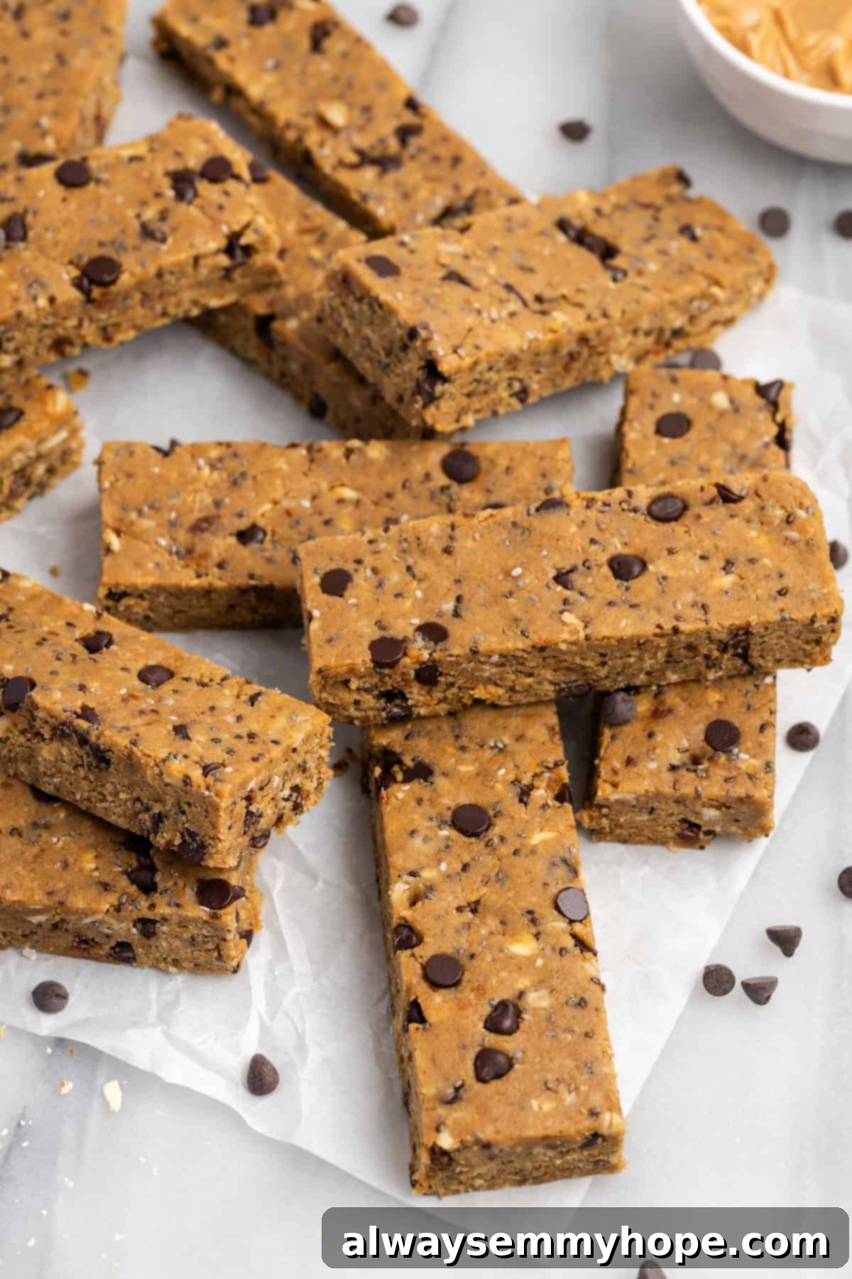 These homemade vegan protein bars are an easy, no-bake recipe that you can customise with your favourite flavours and mix-ins. So tasty! Pile of homemade vegan chocolate chip protein bars on parchment paper