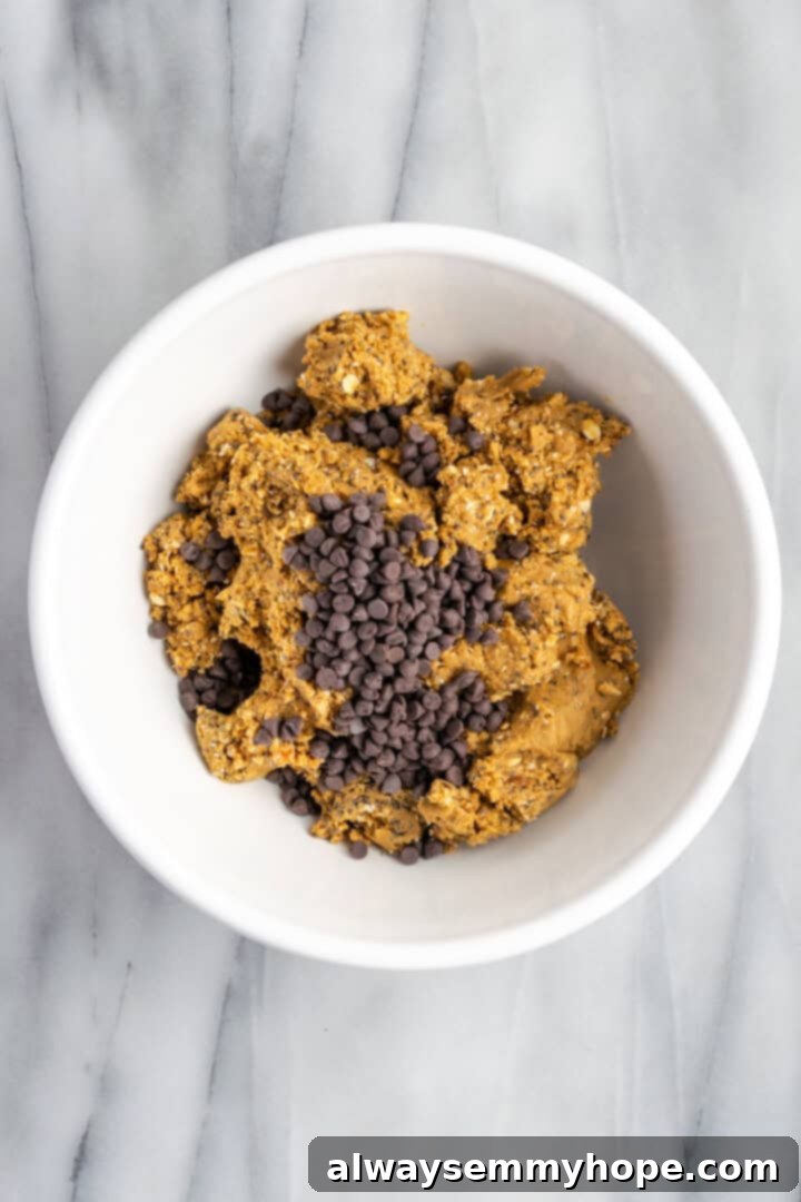 These homemade vegan protein bars are an easy, no-bake recipe that you can customise with your favourite flavours and mix-ins. So tasty! Mini chocolate chips folded into a bowl of protein bar mixture