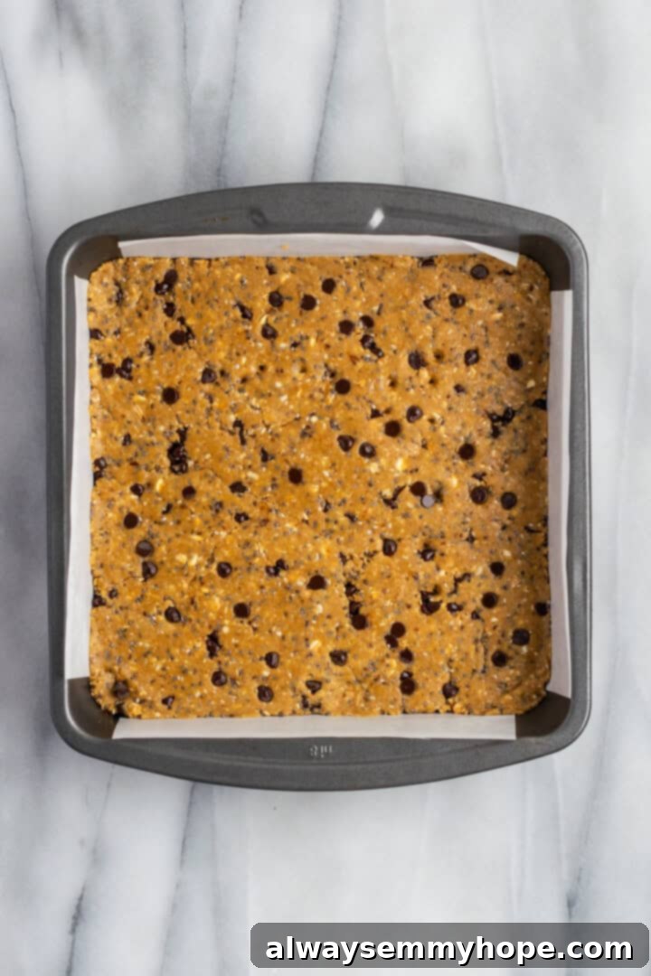 These homemade vegan protein bars are an easy, no-bake recipe that you can customise with your favourite flavours and mix-ins. So tasty! Protein bar mixture pressed evenly into a square pan lined with parchment paper