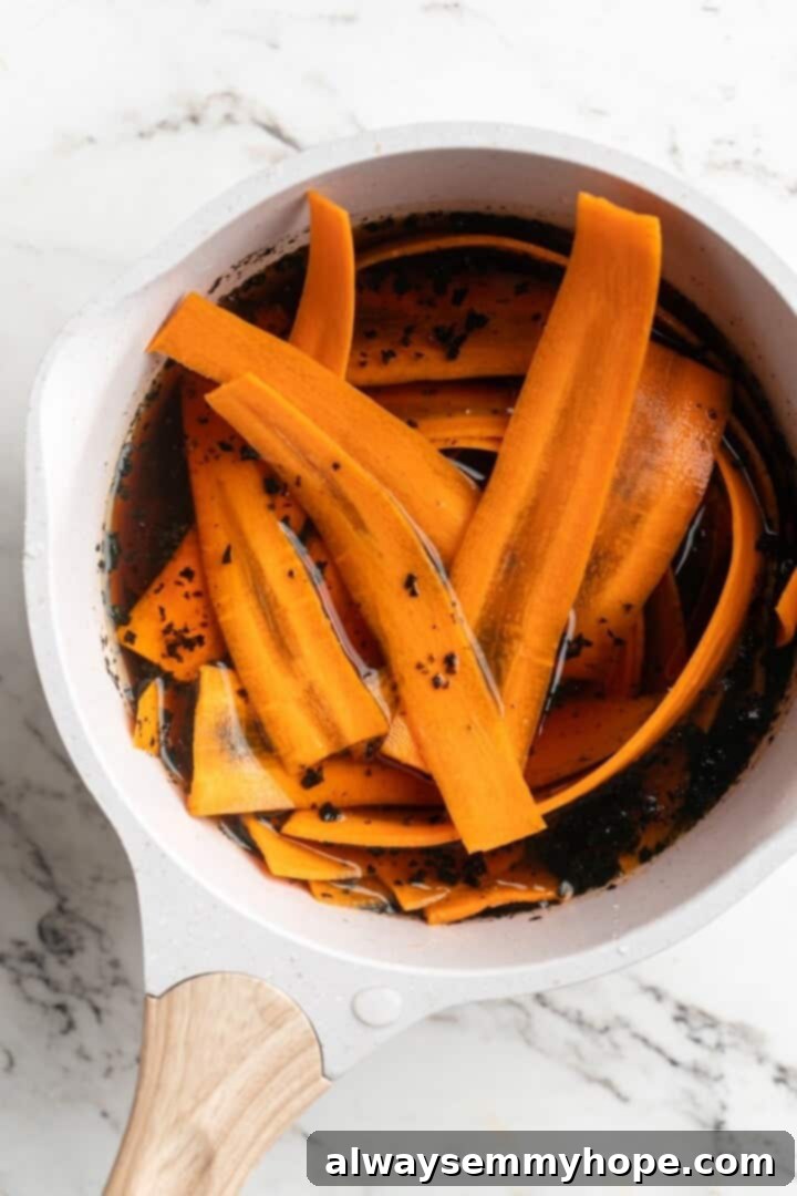Carrot slices and a vibrant brine mixture gently simmering in a saucepan on the stovetop.