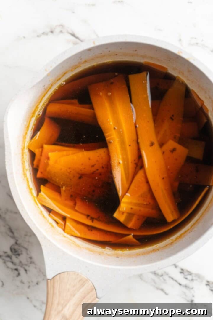 Cooked carrot lox mixture cooling completely in a saucepan, absorbing the savory brine.