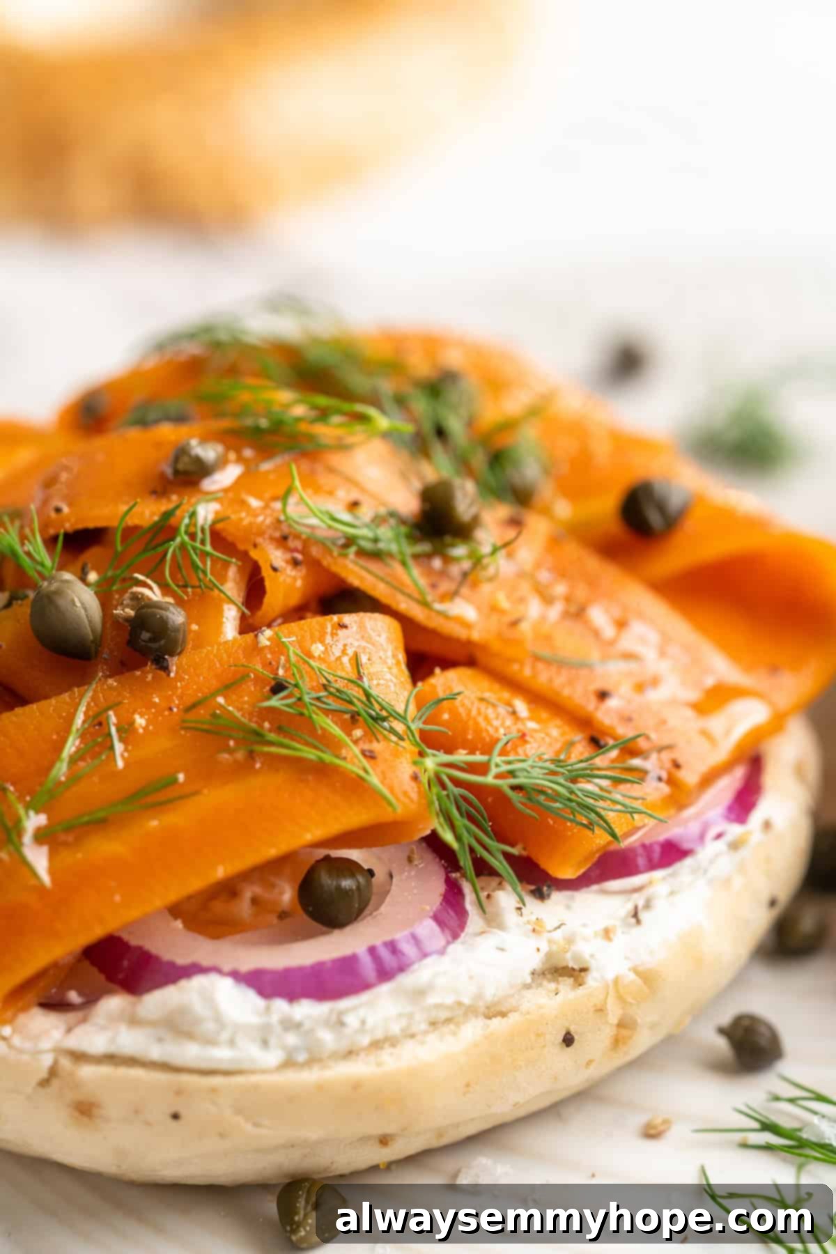 Another appealing perspective of a toasted bagel adorned with creamy vegan cream cheese and vibrant carrot lox, artfully arranged and ready to be enjoyed.
