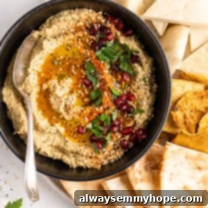 Overhead view of baba ghanoush in black bowl with spoon, surrounded by pitas
