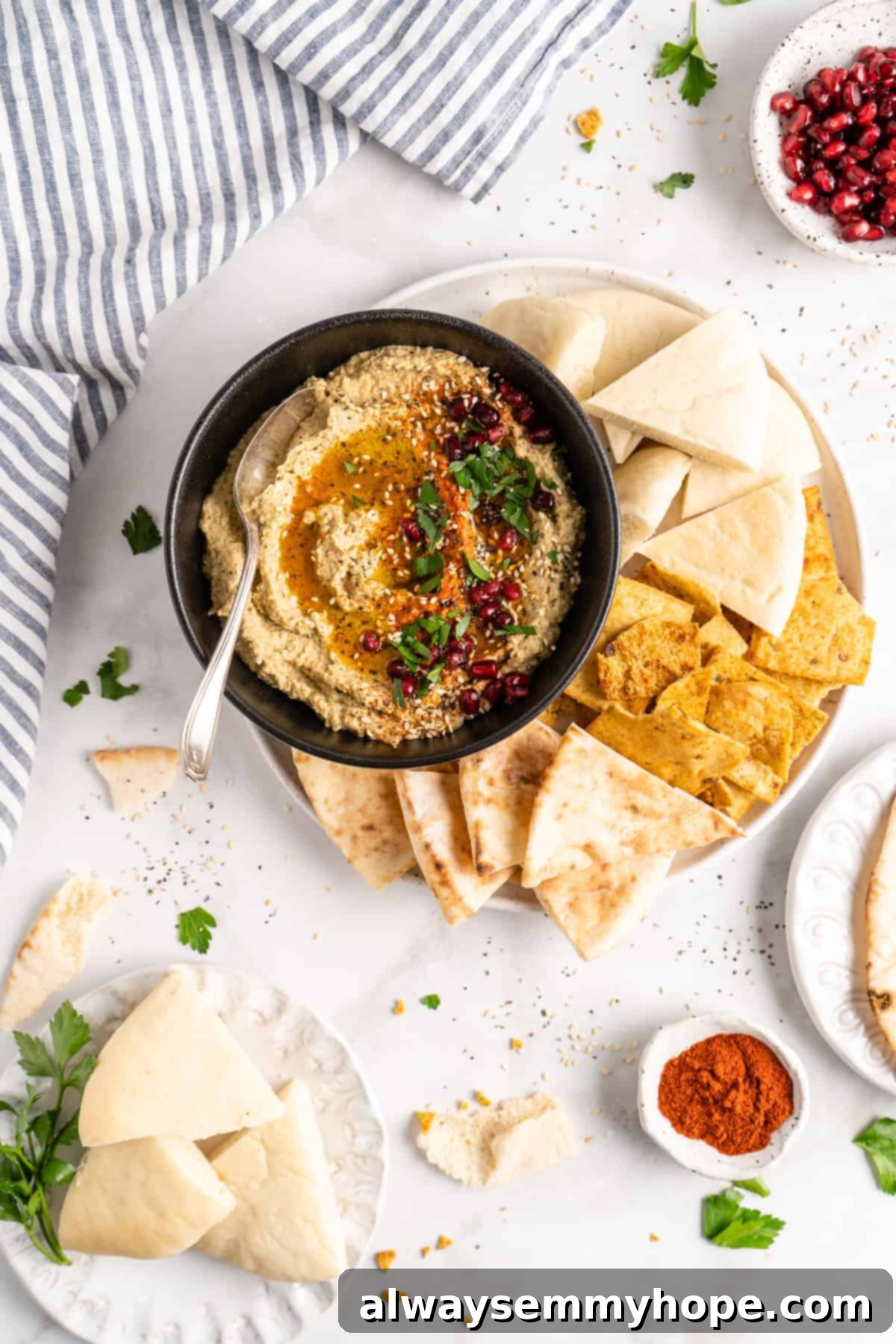 Overhead view of baba ghanoush in bowl with spoon and pita bread, garnished