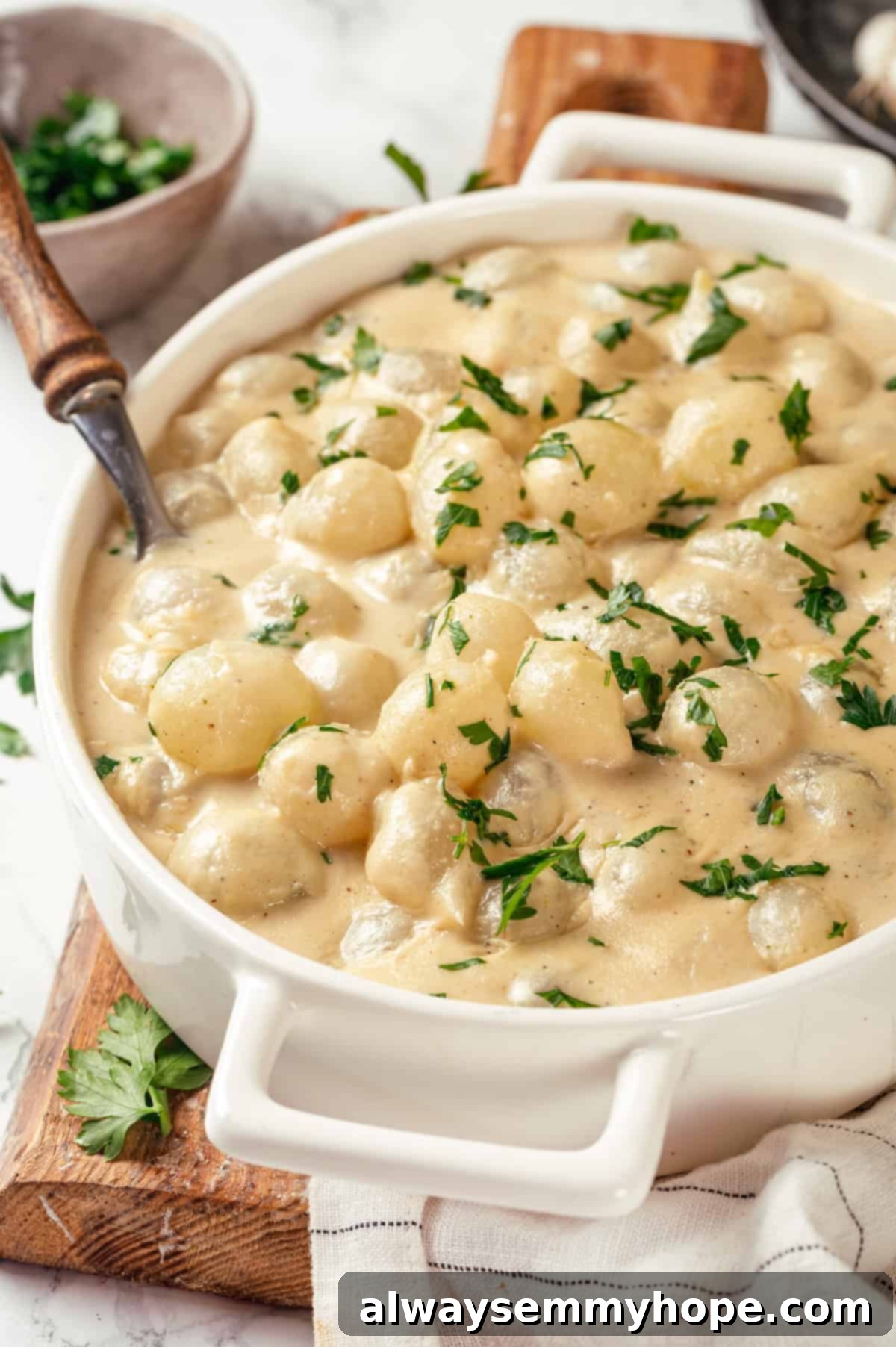 These creamed onions are sweet, savoury, and rich. A stovetop recipe perfect for holiday dinners but easy enough for a weeknight! Dish of creamed onions with spoon