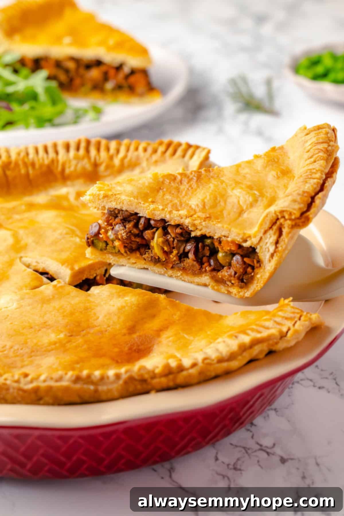 Lifting slice of vegan tourtière from pan, showcasing its flaky crust and rich filling