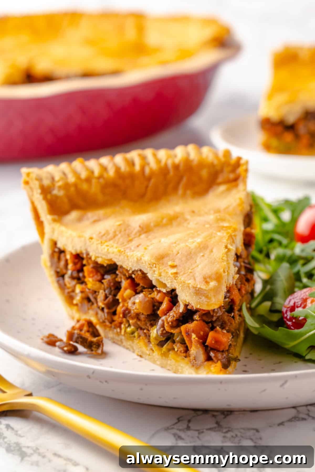 Slice of vegan tourtière on plate with fresh green salad