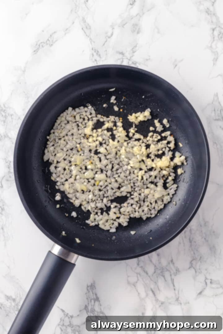 Onion and garlic cooking in a skillet, turning translucent