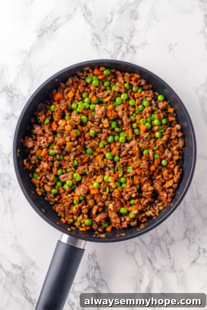 Thickened filling for tourtière in skillet with peas added