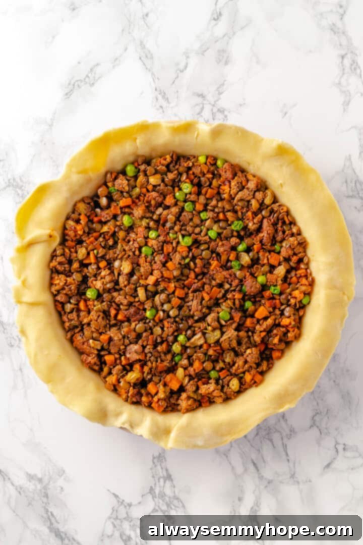 Savory vegan tourtière filling added to the bottom pie crust in a dish