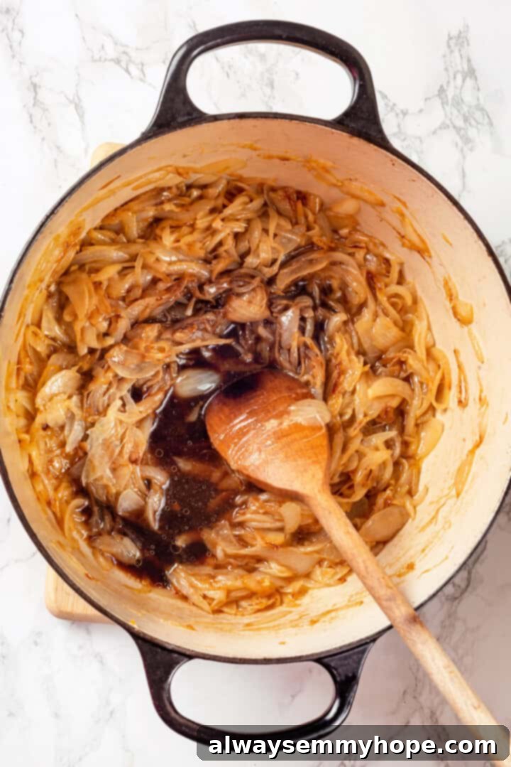 This vegan French onion soup recipe is full of rich, savoury flavour, and lots of melty cheese! The perfect cozy dinner for a chilly day. Overhead view of balsamic vinegar and wine added to pot of caramelized onions