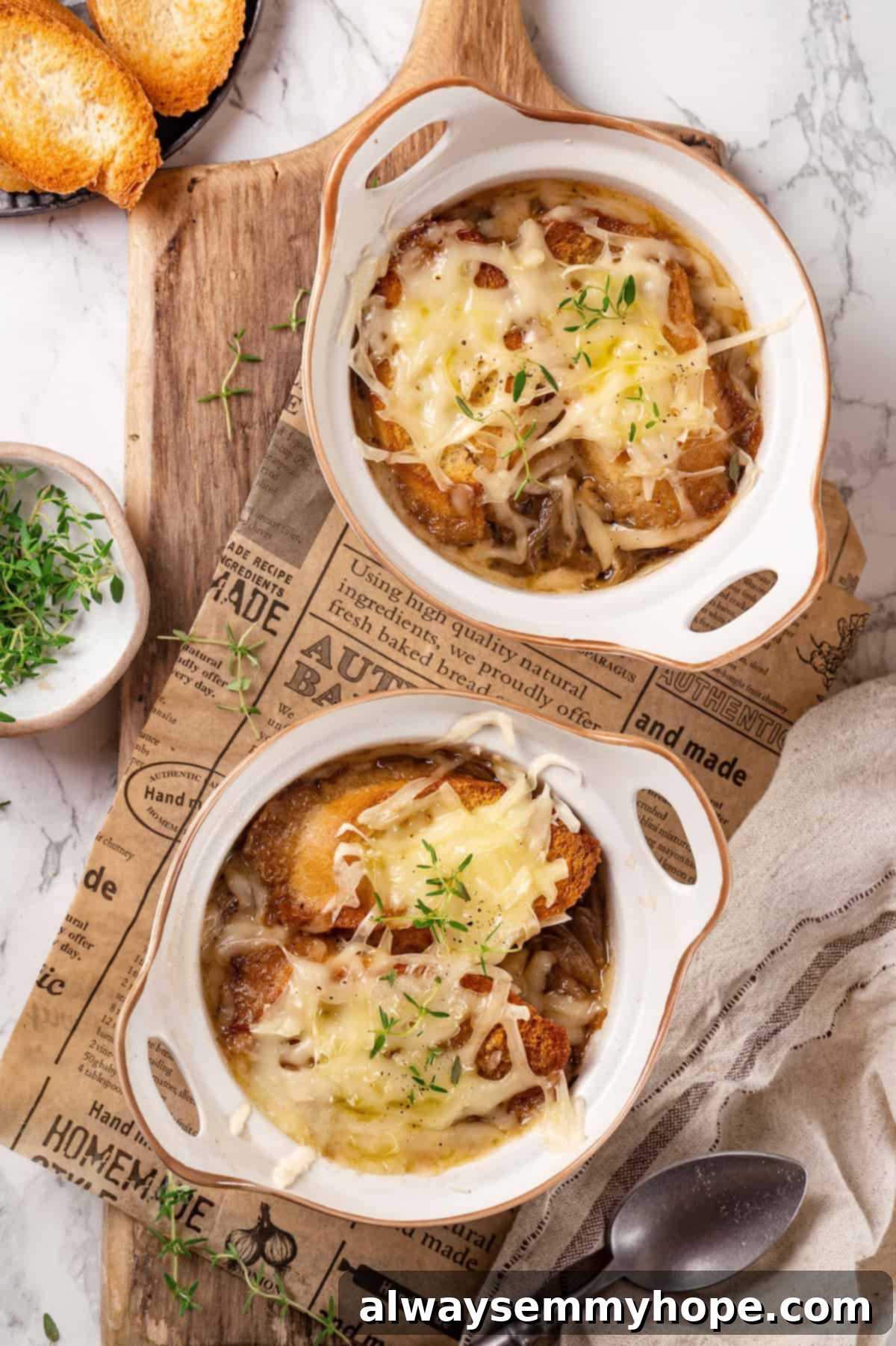 This vegan French onion soup recipe is full of rich, savoury flavour, and lots of melty cheese! The perfect cozy dinner for a chilly day. Overhead view of French onion soup in two bowls with melted vegan cheese and toasted bread