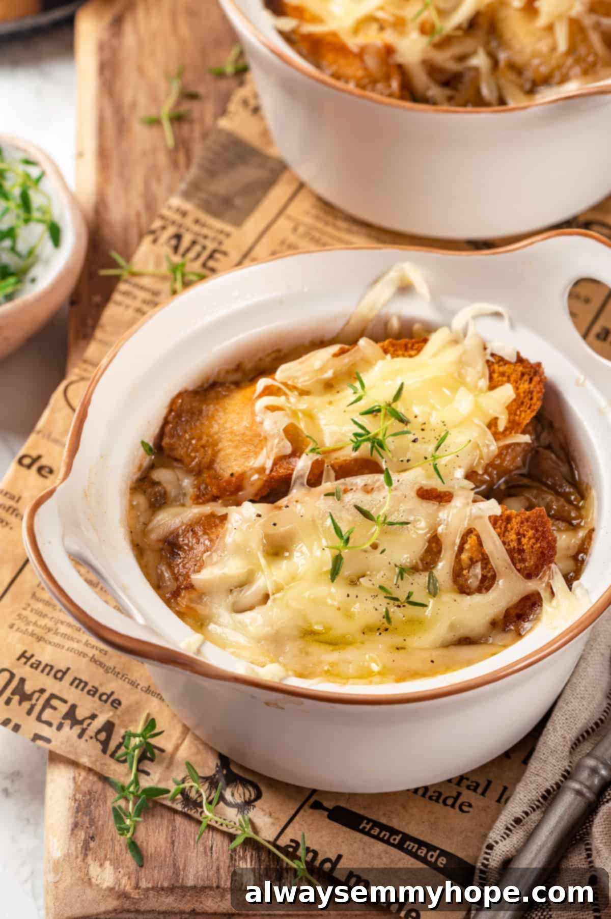 This vegan French onion soup recipe is full of rich, savoury flavour, and lots of melty cheese! The perfect cozy dinner for a chilly day. Homemade French onion soup in bowls with fresh thyme garnish