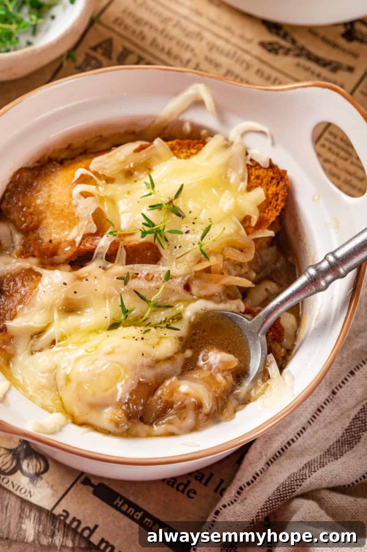 This vegan French onion soup recipe is full of rich, savoury flavour, and lots of melty cheese! The perfect cozy dinner for a chilly day. Vegetarian French onion soup in bowl with spoon, ready to be enjoyed