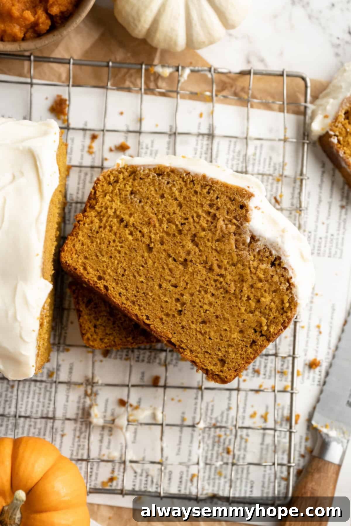 Vegan pumpkin bread with cream cheese frosting is moist, full of cozy spices and the frosting takes it over the top. So easy to make too! Multiple slices of vegan pumpkin bread with thick cream cheese frosting stacked artfully on a wire cooling rack, showcasing its moist texture.