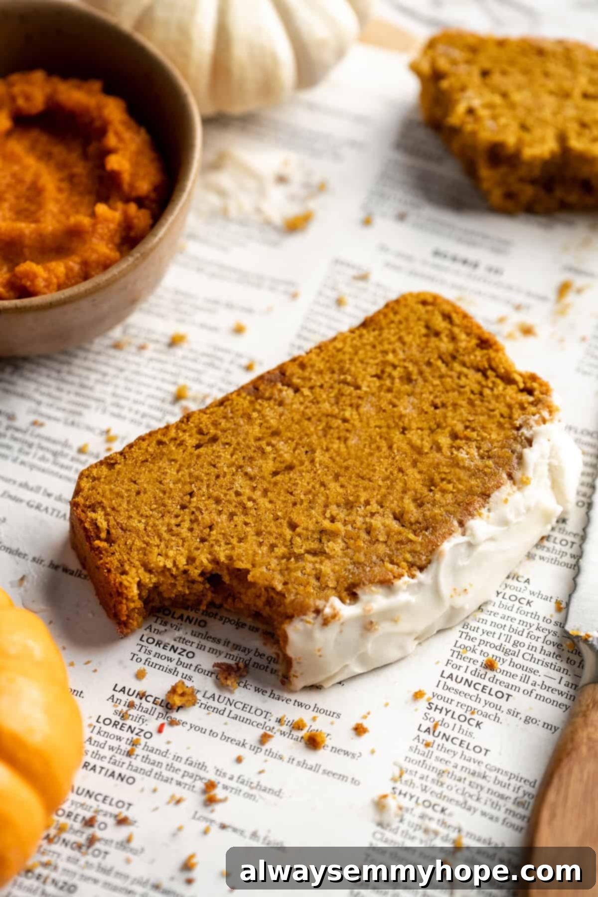 Vegan pumpkin bread with cream cheese frosting is moist, full of cozy spices and the frosting takes it over the top. So easy to make too! A delectable slice of vegan pumpkin bread with cream cheese frosting, showing a bite taken out of the corner, highlighting its moist texture and rich frosting.