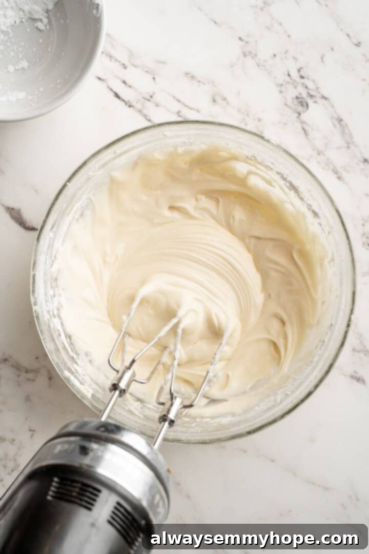 Vegan pumpkin bread with cream cheese frosting is moist, full of cozy spices and the frosting takes it over the top. So easy to make too! Close-up of a hand mixer beating vegan cream cheese, vegan butter, vanilla, salt, powdered sugar, and cornstarch in a bowl to create smooth, fluffy frosting.