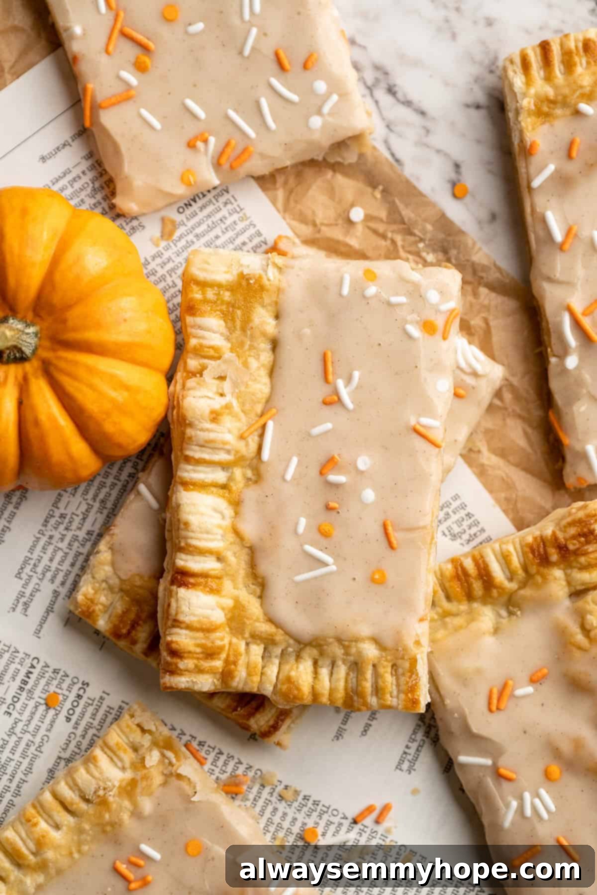 A cozy pumpkin-spiced filling is tucked into flaky vegan puff pastry to make these easy and delicious homemade pumpkin pop tarts! Overhead view of a full tray of homemade vegan pumpkin pop tarts, frosted and perfectly baked.