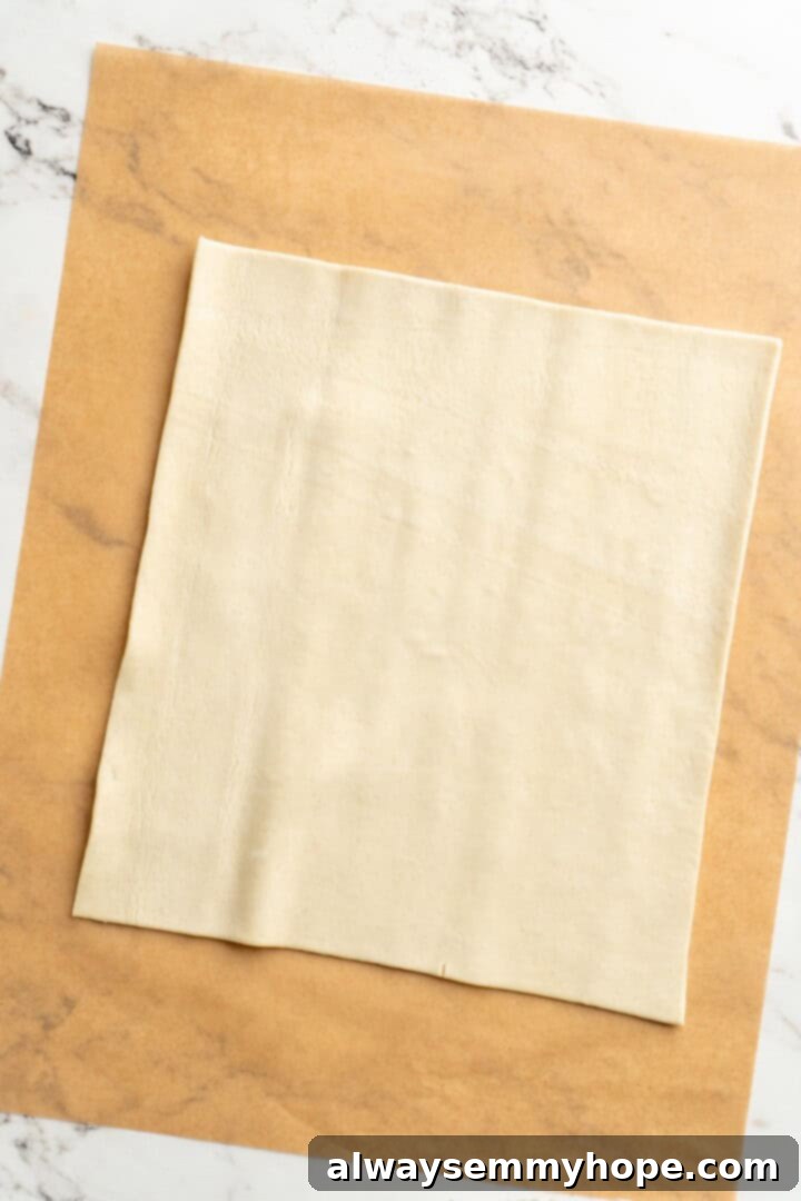 A cozy pumpkin-spiced filling is tucked into flaky vegan puff pastry to make these easy and delicious homemade pumpkin pop tarts! Rolled out vegan puff pastry sheet on parchment paper, ready for filling.