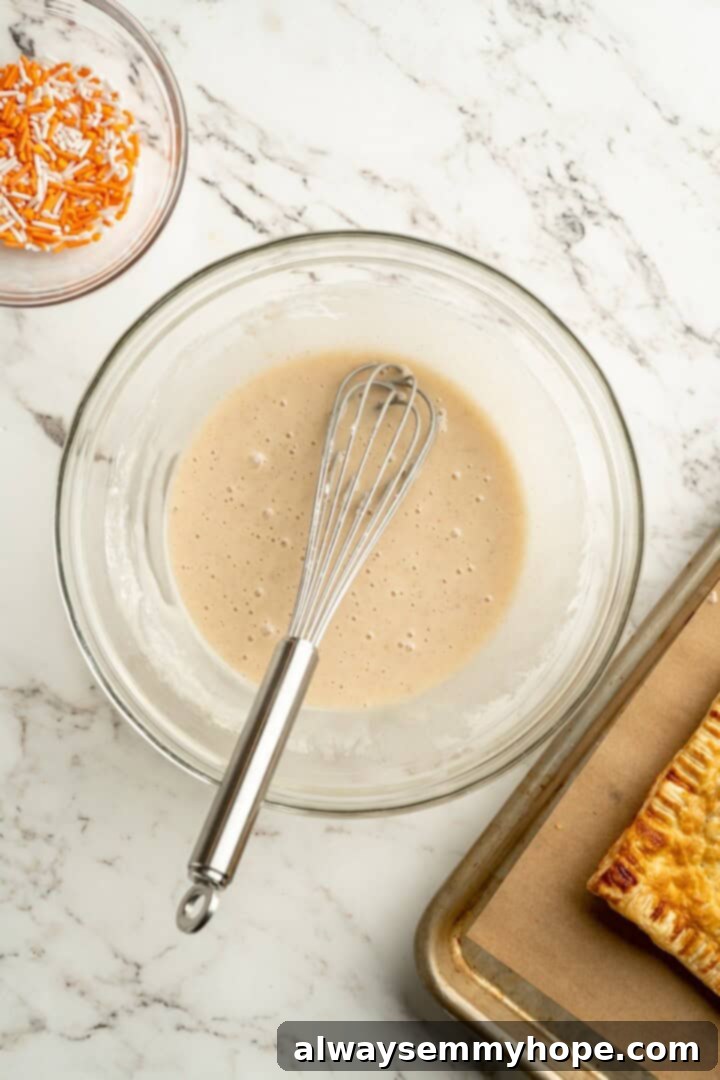 A cozy pumpkin-spiced filling is tucked into flaky vegan puff pastry to make these easy and delicious homemade pumpkin pop tarts! Icing mixture in a bowl with a whisk, ready for frosting.