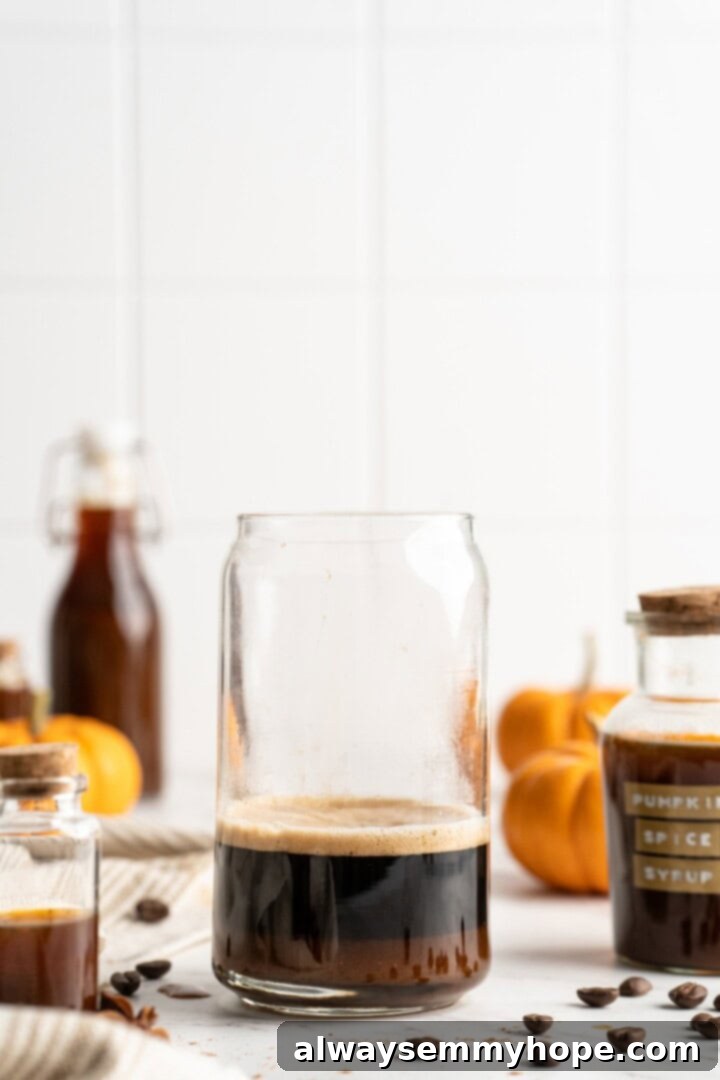 This vegan pumpkin spice latte recipe is a homemade version of the coffee house favourite. It's just as cozy and delicious as the original! Espresso being poured into a clear glass, ready for an iced pumpkin spice latte.