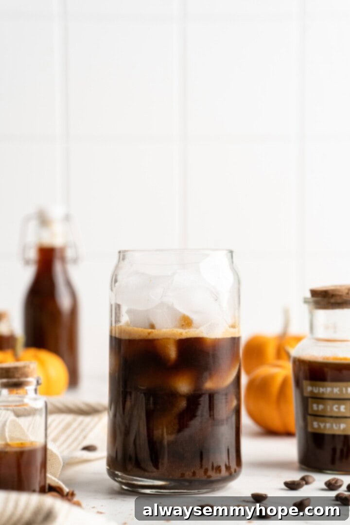 This vegan pumpkin spice latte recipe is a homemade version of the coffee house favourite. It's just as cozy and delicious as the original! Pumpkin spice syrup being added to a glass with espresso, preparing for a delicious vegan latte.