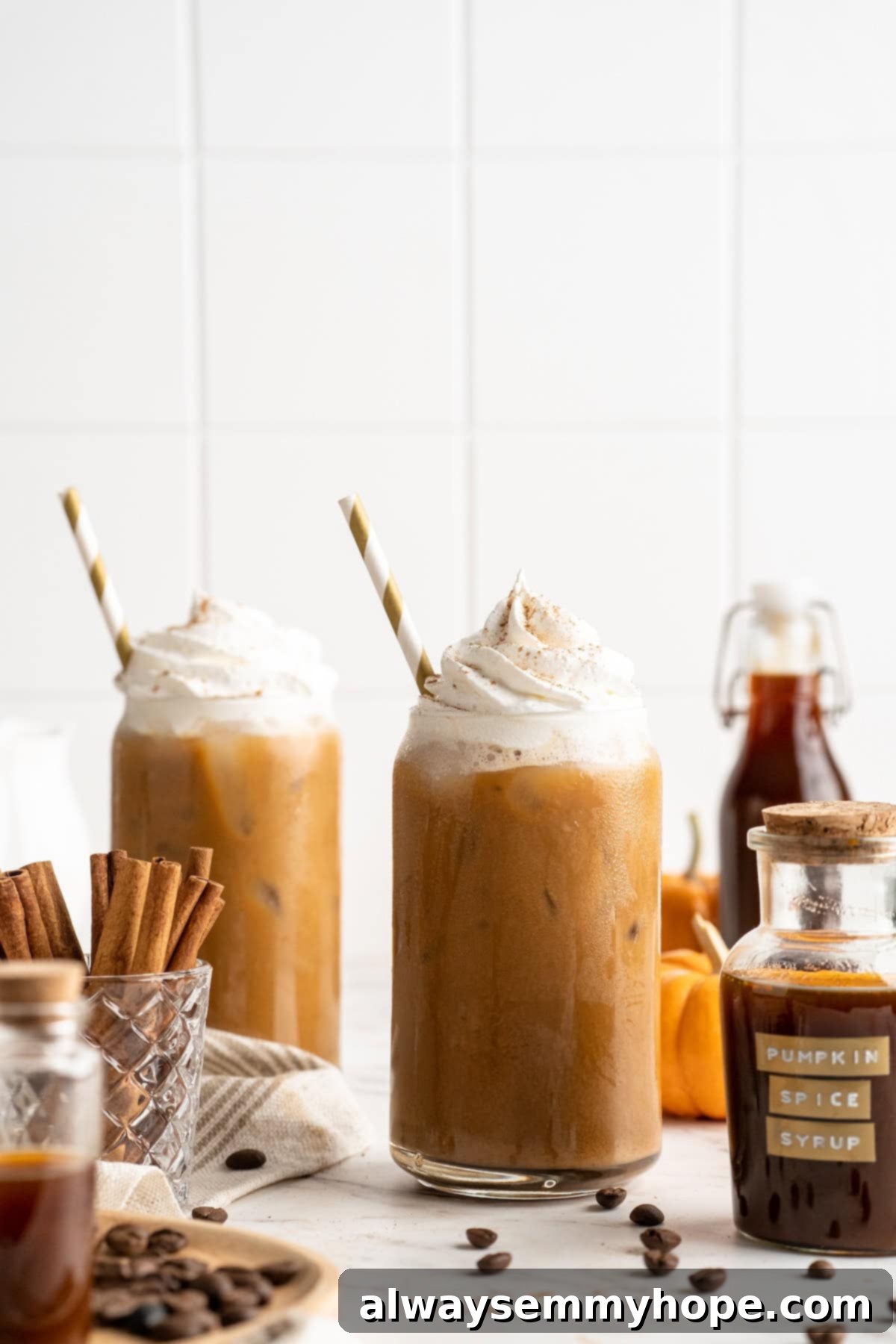 This vegan pumpkin spice latte recipe is a homemade version of the coffee house favourite. It's just as cozy and delicious as the original! Two perfectly garnished vegan pumpkin spice lattes with whipped cream and pumpkin pie spice, ready to be enjoyed.