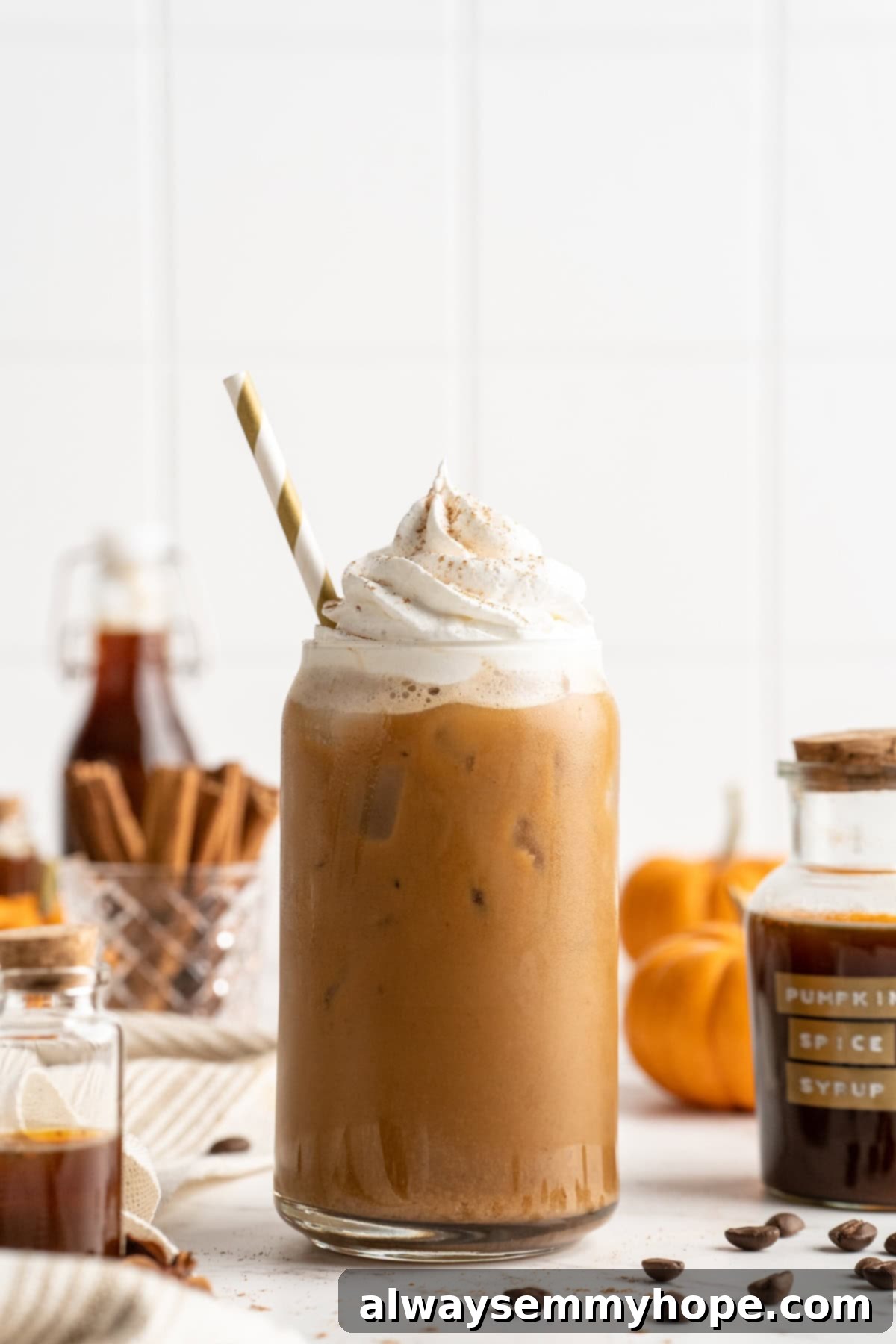 This vegan pumpkin spice latte recipe is a homemade version of the coffee house favourite. It's just as cozy and delicious as the original! A single homemade pumpkin spice latte with a straw and vegan whipped cream, ready for a delicious sip.