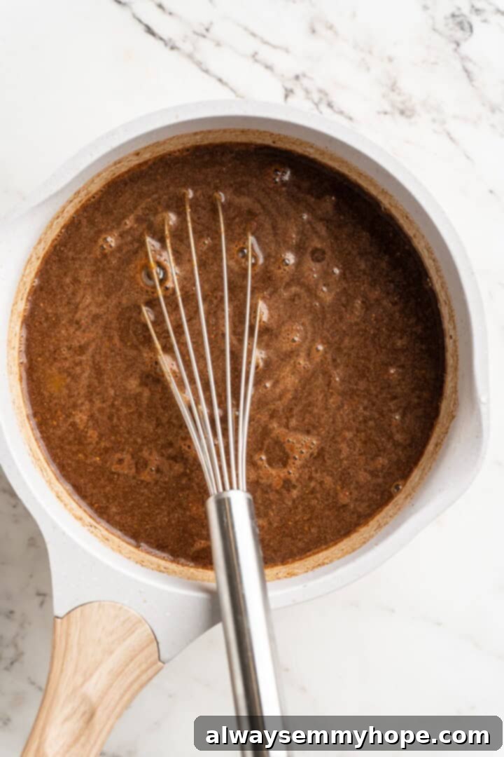Step 1: Combining and Heating Ingredients for Pumpkin Spice Syrup Whisking homemade pumpkin spice syrup ingredients in a saucepan over medium heat
