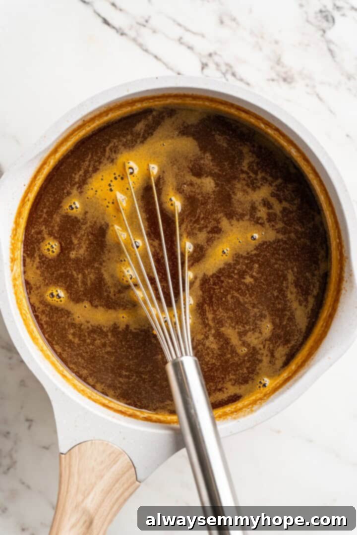 Step 2: Bringing the Syrup to a Boil Pumpkin spice syrup mixture actively boiling in a saucepan on the stove