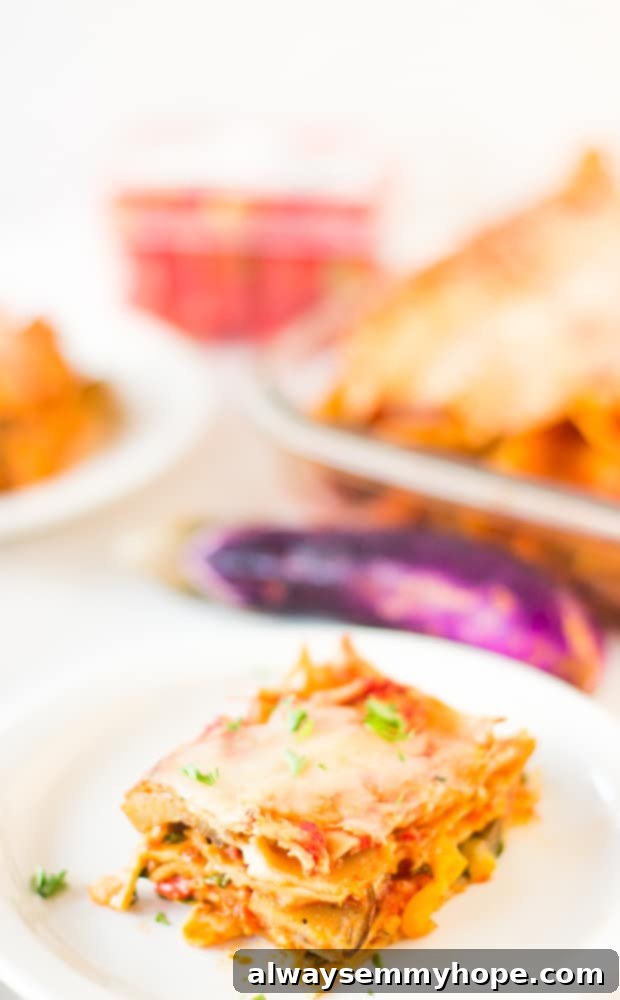 This whole wheat, hearty, loaded Vegetable Lasagna is delicious, cheesy and completely customisable! Perfect for a comforting dinner. A square of lasagna on a white plate.