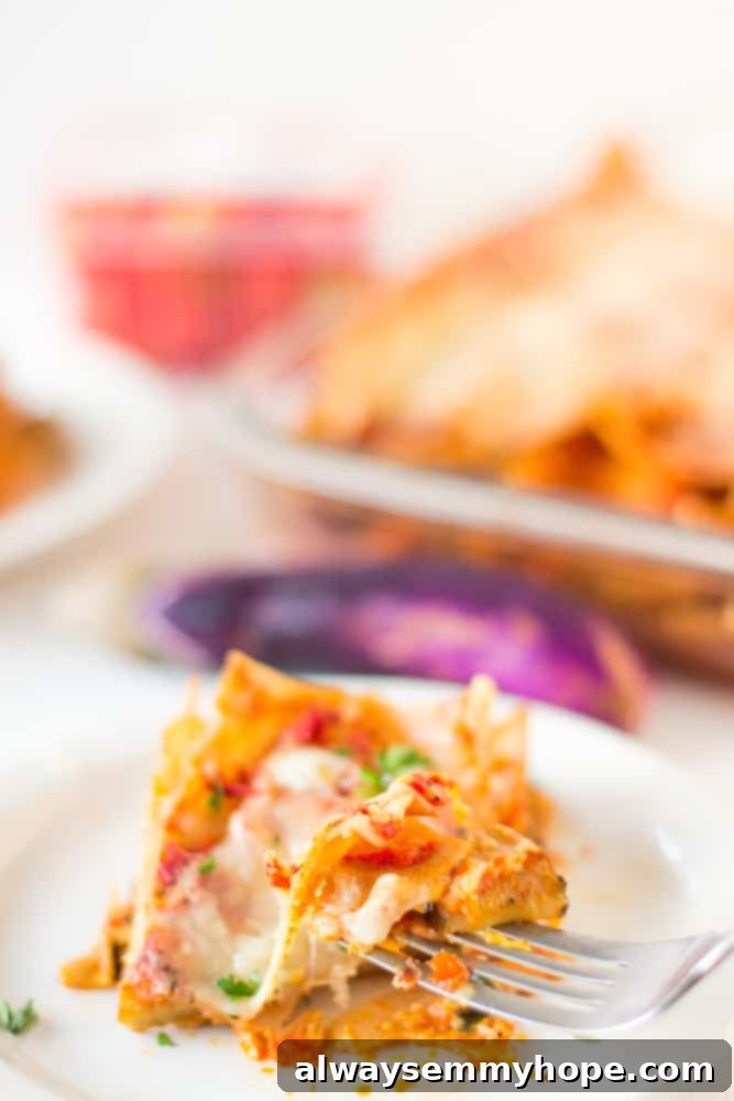 This whole wheat, hearty, loaded Vegetable Lasagna is delicious, cheesy and completely customisable! Perfect for a comforting dinner. A fork scooping up some lasagna.