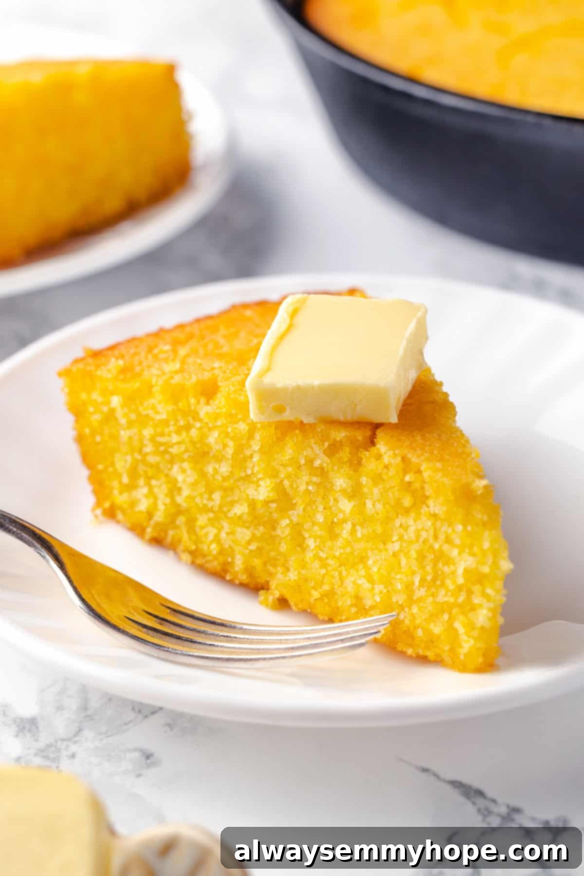 This vegan corn pone is crispy on the outside, tender on the inside, and so delicious! If you like cornbread, you’ll love this recipe. Slice of corn pone on plate with pat of butter on top, showcasing crispy edges and tender crumb