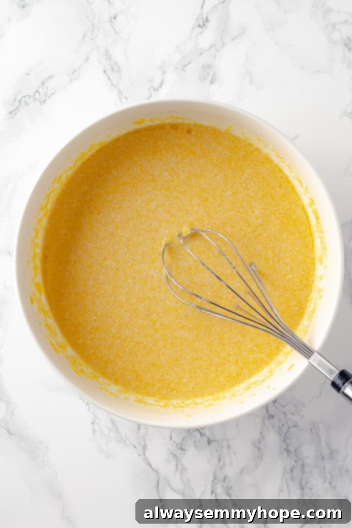 This vegan corn pone is crispy on the outside, tender on the inside, and so delicious! If you like cornbread, you’ll love this recipe. Vegan corn pone batter in a mixing bowl with a whisk, after wet ingredients are added