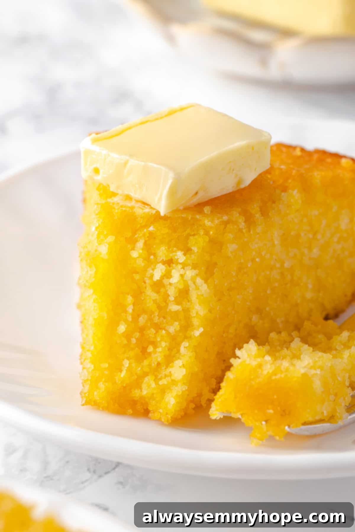 This vegan corn pone is crispy on the outside, tender on the inside, and so delicious! If you like cornbread, you’ll love this recipe. Close up shot of a pat of vegan butter melting on a warm piece of corn pone