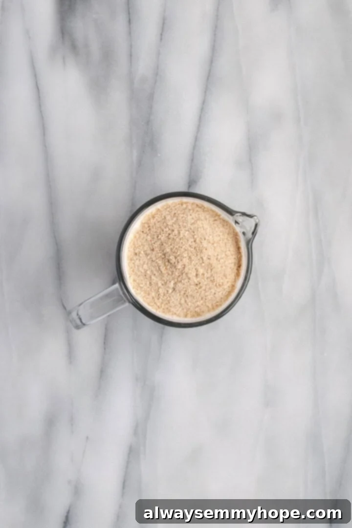 Warm liquids and add psyllium husk for gluten-free rolls Psyllium husk powder being stirred into warm non-dairy milk and water in a measuring cup