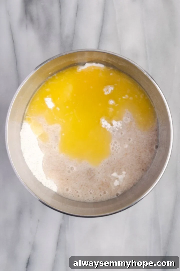 Mix dry ingredients with wet ingredients for gluten-free dough Wet ingredients being poured into dry ingredients in a stand mixer bowl