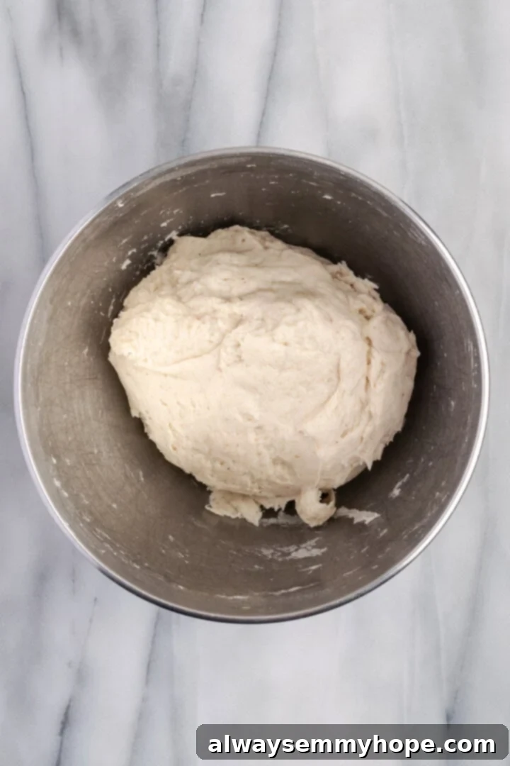 Knead gluten-free dough until smooth Smooth, cohesive dough for gluten-free dinner rolls in a mixing bowl after kneading