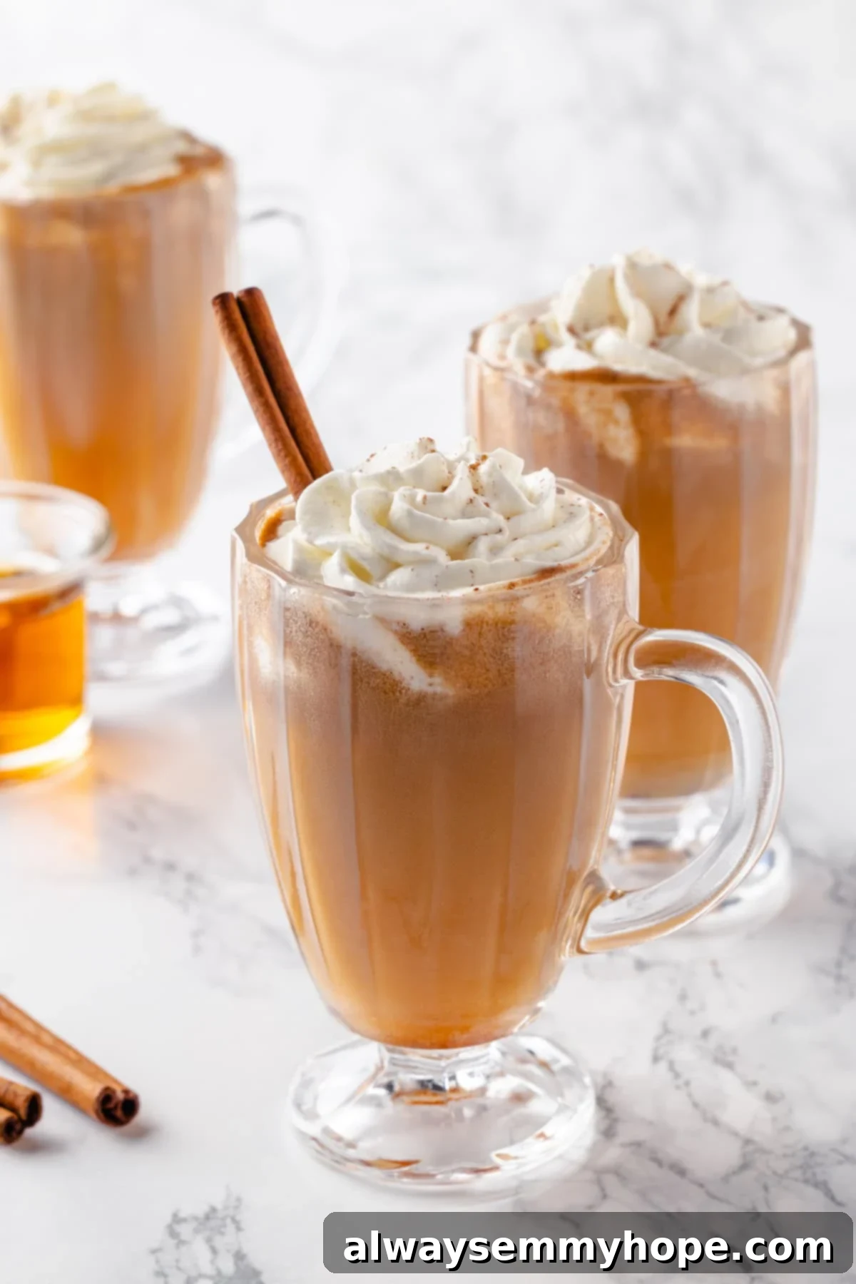 A trio of beautiful hot buttered rum drinks, ideal for sharing during the holidays. Three glass mugs filled with steaming hot buttered rum, perfectly garnished and ready for a festive celebration.