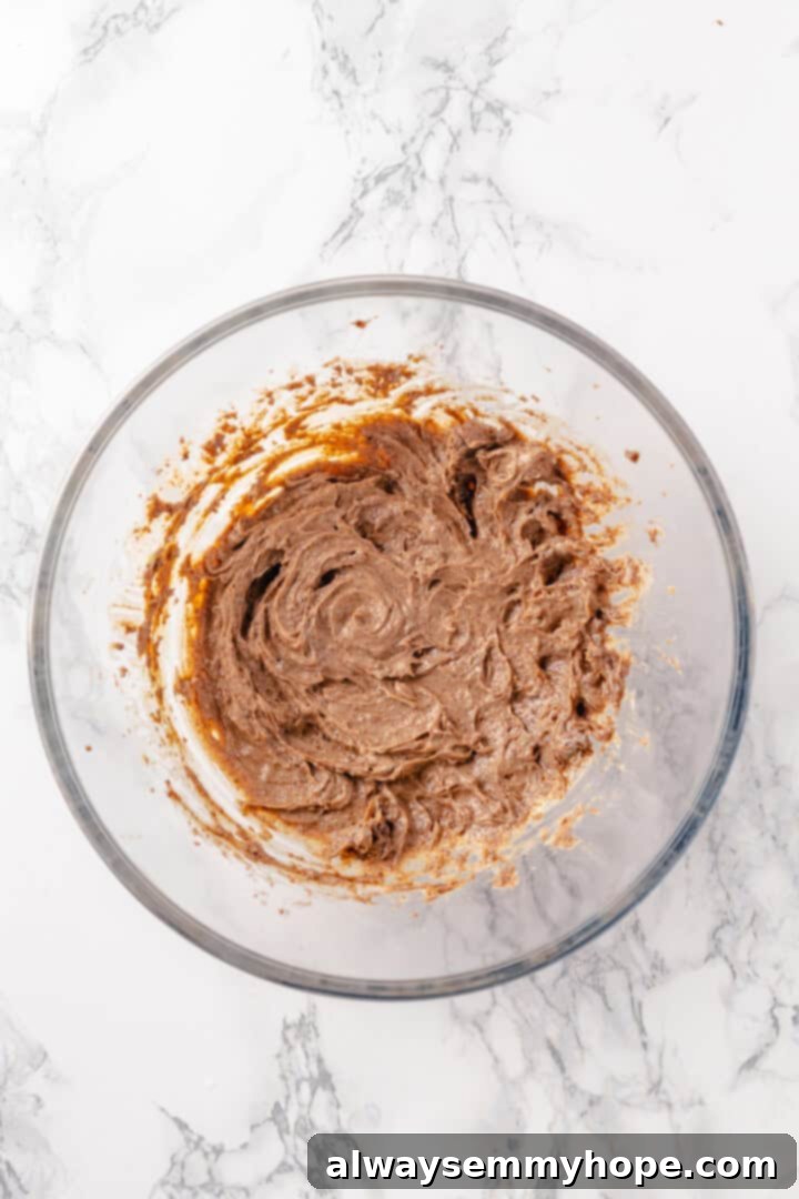 Mixing the base ingredients for a rich and spiced vegan hot buttered rum. Overhead shot of vegan butter, brown sugar, and spices being mixed in a bowl for the hot buttered rum base.