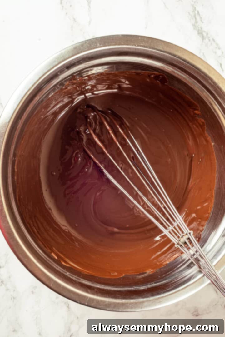 A Dubai chocolate bar is filled with crispy kataifi and a rich, creamy mixture of pistachio and tahini. Here’s how to make them at home! Overhead view of melted chocolate in bowl with whisk
