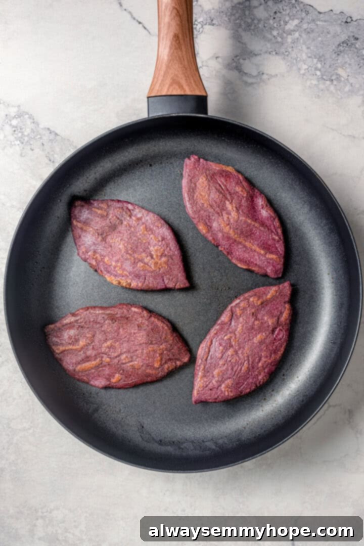 Easy tlacoyos filled with black beans. Top this homemade and vegan spin on Mexican street food with diced avocado, salsa and vegan cheese. Cooking tlacoyos in a skillet.